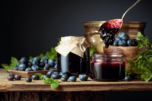 Blueberry jam with fresh berries on an old wooden table. Copy space.
