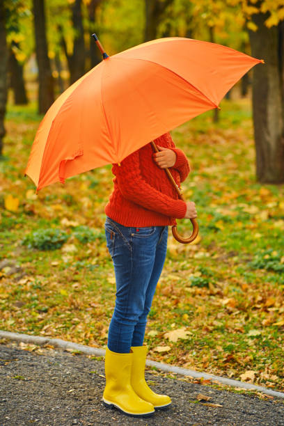 istock Funny unrecognizable kid under an orange umbrella 1433306320