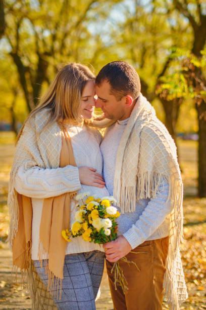 pregnant woman and man at sunny warm autumn park - human pregnancy couple prenatal care heterosexual couple imagens e fotografias de stock