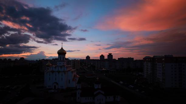 change day to night transition traffic on street and multi-storey residential houses. cityscape minsk skyline with russian orthodox church. 4k cloudy sky with clouds in motion above multi-storey houses. high-rise buildings at sunset - day to sunset imagens e fotografias de stock