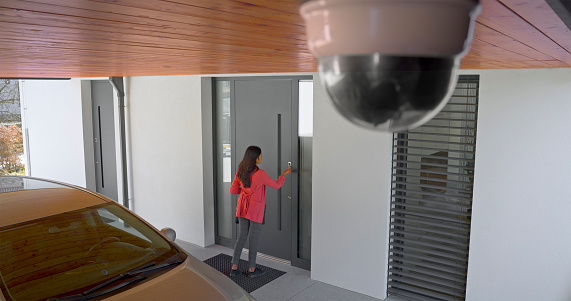 Young woman's index finger pressing on fingerprint scanner to enter her house.