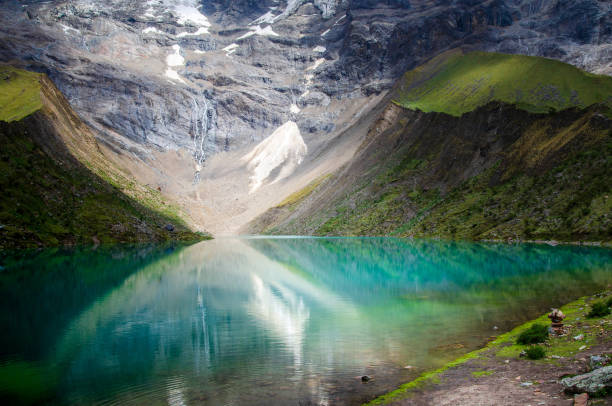 Humantay lake in Peru in the Andes amazing scenic view of remote Peruvian tourist attraction Humantay Lake deep in the Andes Mountains of Peru. Humantay Lake is a lovely high altitude trail that leads to a spectacular turquoise lake that sits at 13,779 feet above sea level, back dropped by the beautiful and massive Humantay Glacier and Humantay Mountain that sits high at 17,956 feet above sea level Sallqantay stock pictures, royalty-free photos & images