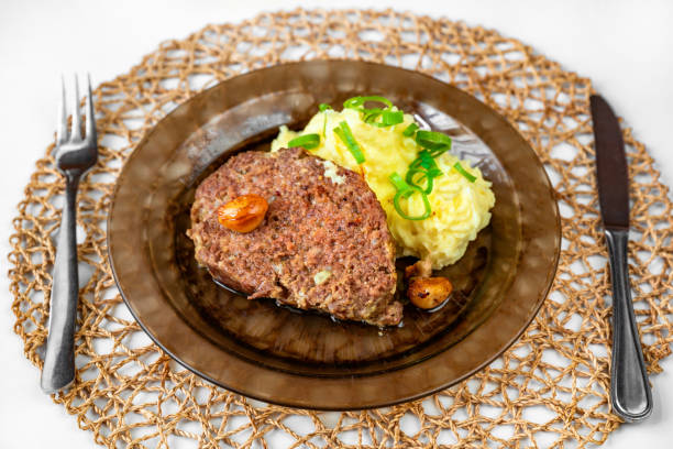 Baked minced beef, garlic and mashed potato on plate, cutlery and bamboo pad. stock photo