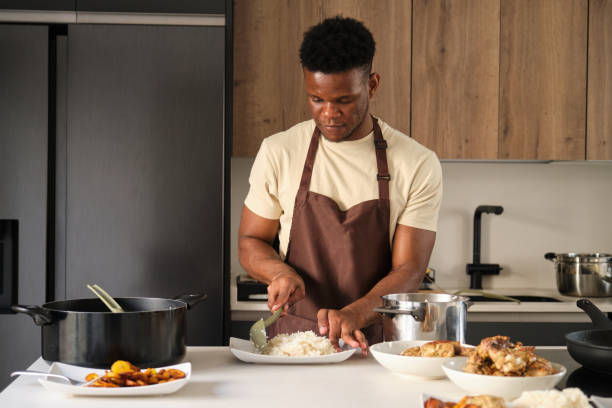istock Young black man serving rice on a plate. 1433310788