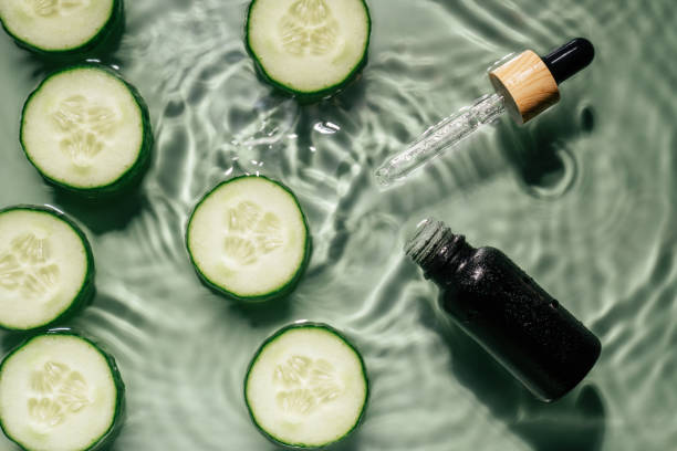 Facial pipette serum black bottle, whey beauty product near cucumber slices in water splashing fresh transparent, flecks stock photo