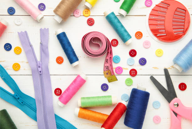 istock Sewing supplies on white background: sewing thread, scissors, a large spool of thread, pieces of cloth, needles,centimeter, buttons. Vertical photo 1433316779