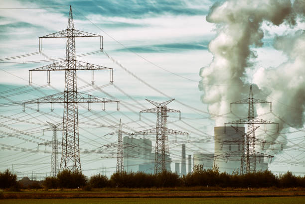 Brown-coal burning power plant with pollution and a group of electricity pylons.