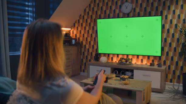 istock Woman switching TV channels with remote control 1433318529