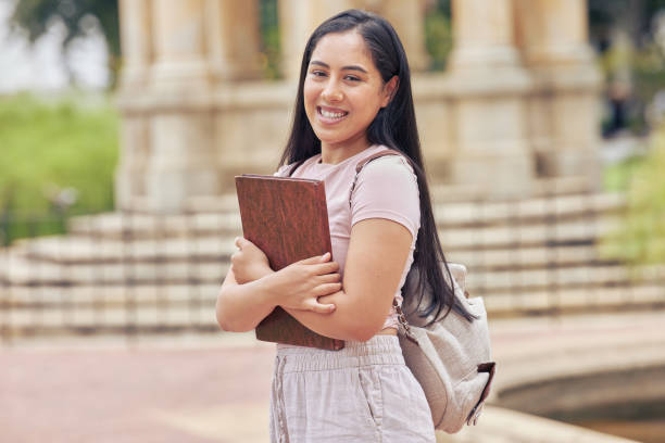 istock One mixed race female student standing outside on her university campus while wearing a backpack. A beautiful young woman holding her digital tablet outdoors while on break between college classes 1433320256