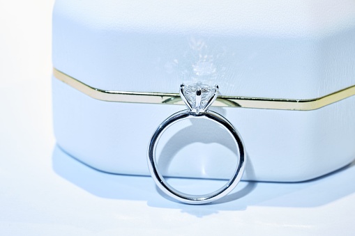 A closeup of a beautiful white gold wedding ring set with a diamond under bright artificial lighting