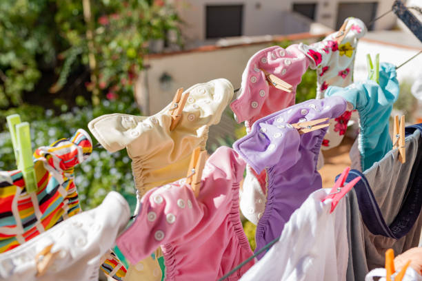 Cloth diapers hanging while drying under the sun on clothesline. Laundry of colorful reusable nappies for babies. stock photo