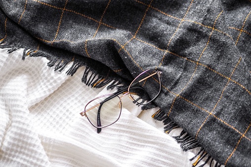 A top view of optical glasses on a white and gray blanket background.