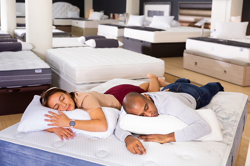 Man and woman fell asleep on new mattress in a furniture store