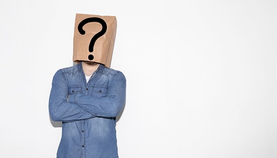A man wearing a brown paper bag over his head with a question mark
