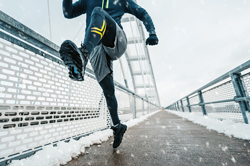 Handsome middle age man with a beard running and exercising outside on extremely cold and snowy day. Sport and fitness motivation theme.