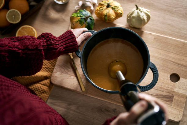 From above of caucasian woman preparing pumpkin soup at home stock photo