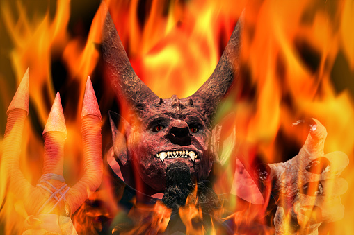 Devil on fire on a dark background. Man in scary devil mask, halloween. Holding out his hand. Hell concept.