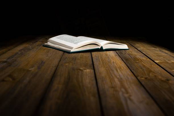 istock Open book on a wooden table on dark background 1433343367