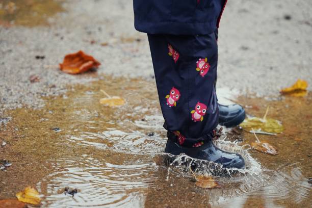 istock Child jumping into rain puddle in autumn 1433345498