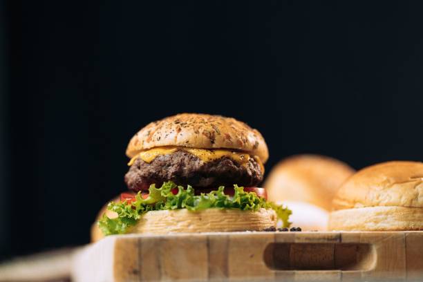 istock Delicious burger with freshly baked buns on wooden board 1433346357