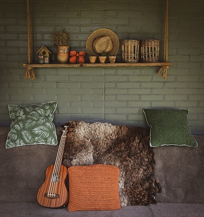 A beautiful interior in rustic colors with a couch and colorful pillows, an ukulele, a hanging shelf