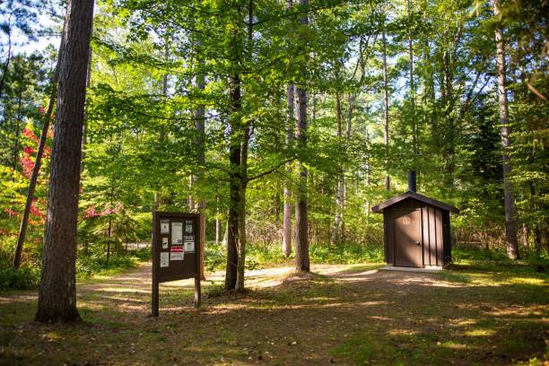 A campground trail with a noticeboard and a restroom in the background