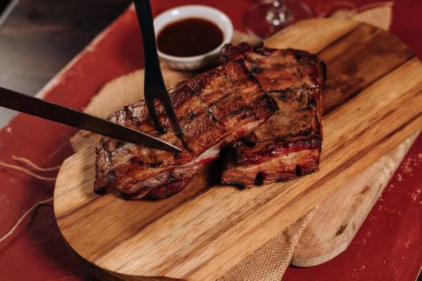 istock Cooked steak being cut on a wooden board by a meat fork and a knife 1433352508