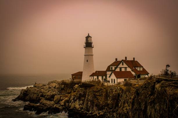 ポートランドのセピアヘッドライトと赤い屋根の家の下に海がある崖の上に - maine lighthouse rock sea ストックフォトと画像