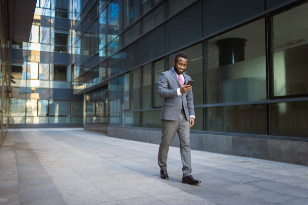 Black businessman texting in front of the office building