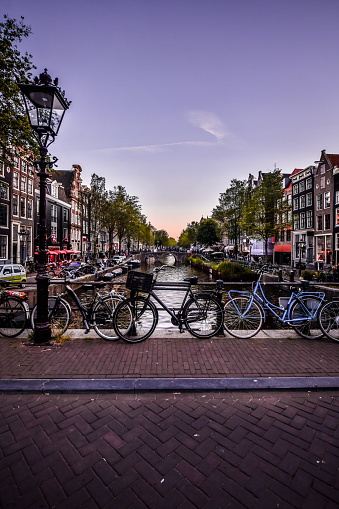 Dusk View Of Bicycles Parked On Bridge Above Canal In Amsterdam, The Netherlands