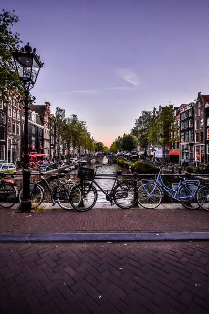 Photo of Dusk View Of Bicycles Parked On Bridge Above Canal In Amsterdam, The Netherlands