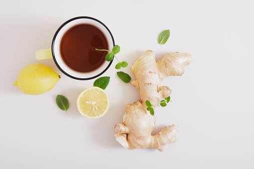cup of rea, ginger root, mint leaves and lemons on a gray background, health benefits of ginger, natural drink for immunity copy space