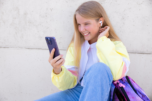 Teenage girl using mobile phone and listening to music