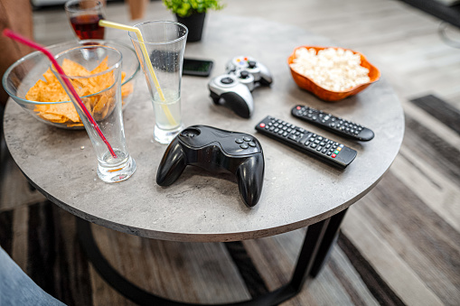 Close up photo of a living room table with two joysticks and some snacks and drinking glasses