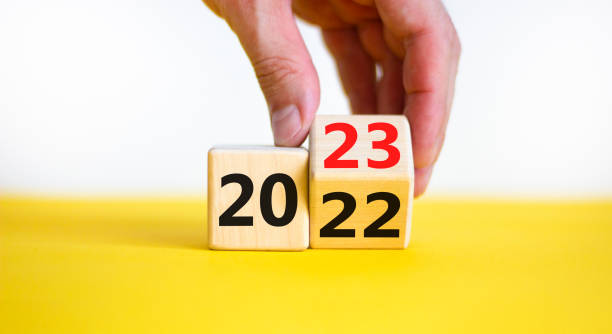 2023 happy new year symbol. Businessman turns a cube, symbolize the change from 2022 to the new year 2023. Beautiful yellow background. Copy space. Business and 2023 happy new year concept. stock photo