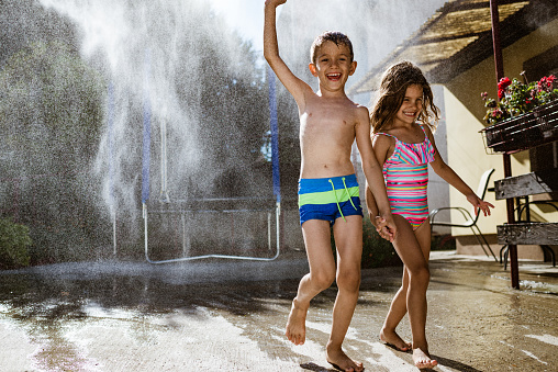 Photo of a happy children spending summer day in their yard, splashing around.