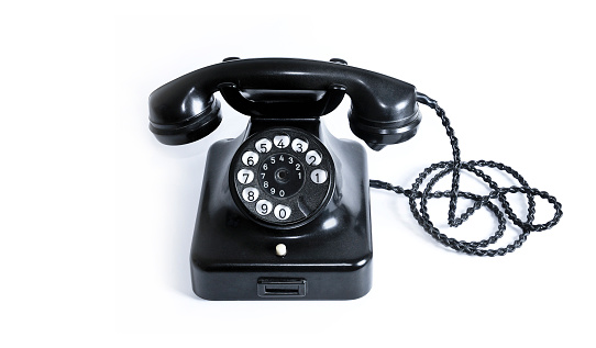 Old black vintage desk phone on white background (built in Germany in the 1940s).