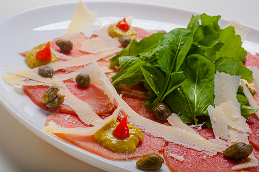 Filet carpaccio served with arugula and capers.