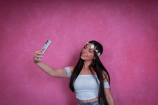 A shot of an attractive happy young woman holding a smartphone and having a photo shoot.