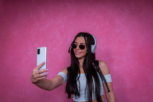 istock Vibrant pink background. The modern lady taking a selfie in the studio. 1433381701