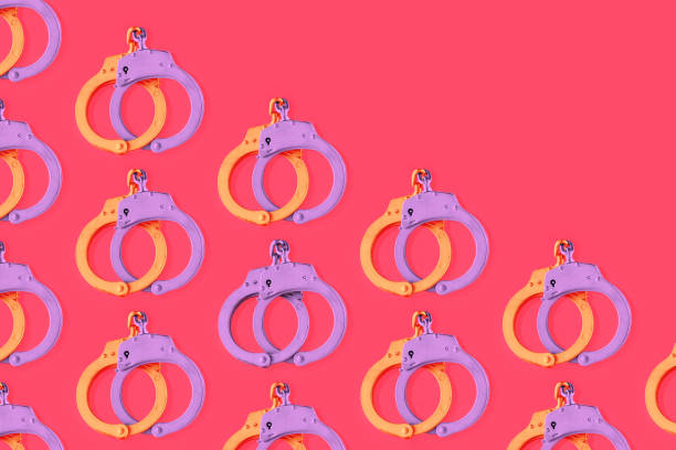 esposas moradas doradas cerradas sobre fondo rojo vibrante aislado. concepto de textura amorosa mínima de diversidad, tolerancia, diferencia, relaciones, parejas lgbtq u homosexuales. patrón de san valentín. - golden handcuffs fotografías e imágenes de stock