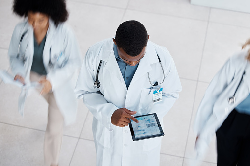 Doctor, digital tablet test and medical worker with research lab data on technology in busy hospital from above. Healthcare man, working people and insurance employee in medicine wellness health room