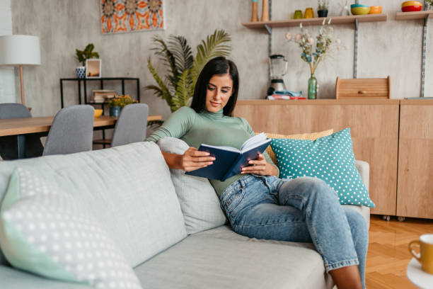 istock Young Woman Sitting On The Sofa And Reading A Book 1433384891