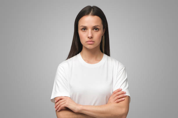 European female standing with arms crossed showing doubt and mistrust on gray background European female standing with arms crossed showing doubt and mistrust isolated on gray background serious photos stock pictures, royalty-free photos & images