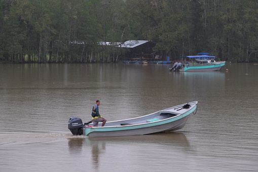 Puntarenas, Costa Rica - September 09, 2022: Man with outboard boat sailing in the rain on the Sierpe River