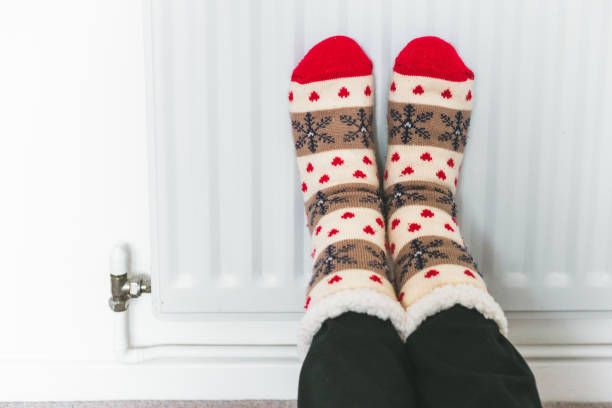 istock Warming her feet on the radiator wearing winter socks 1433387248