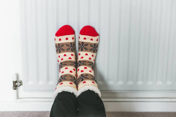 istock Warming her feet on the radiator wearing winter socks 1433387282