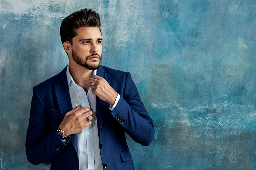 Young handsome businessman posing in elegant fashionable clothes looking away. Portrait of bearded man. A lot of copy space on the background.