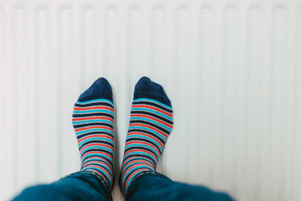 istock Warming his feet on the radiator wearing stripy socks 1433391253