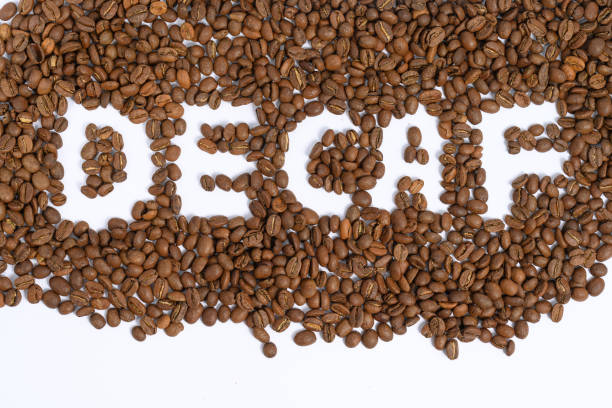 The inscription between the coffee beans is caffeine-free coffee. Inscription between coffee beans - decaffeinated coffee, texture of coffee beans with inscription. decaffeinated stock pictures, royalty-free photos & images